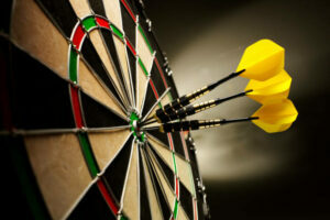 Three yellow darts hitting the target in a game of darts scoring a bulls eye.
